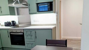 Une cuisine compacte équipée d’une cuisinière, d’un four, d’un four à micro-ondes et d’une petite table à manger avec des chaises.
