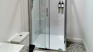 Une salle de bain moderne avec une douche à parois de verre, des toilettes blanches et un lavabo.