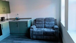 Eine moderne Küche mit einem grauen Sofa und einem Fenster.