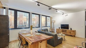 Un soggiorno moderno con tavolo da pranzo in legno, divano e mobile TV.