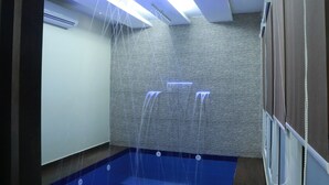 A modern bathroom with a blue floor, a wall-mounted air conditioner, and a shower area with a blue light.