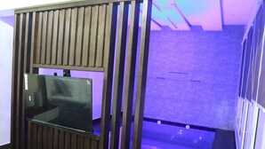 A modern room with a glass partition, a wooden panel design, and a visible bathtub area.