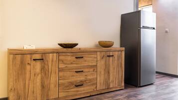 A wooden cabinet with drawers and two bowls on top, a black refrigerator, and a wooden floor.