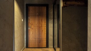 A hallway with a wooden door, a concrete wall, and a wooden floor. - Apartment 8 (Lovech)