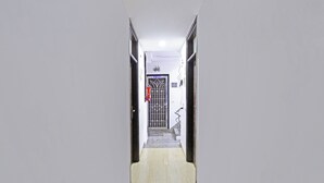 Un pasillo estrecho con suelo de baldosas que conduce a una puerta con reja de metal.