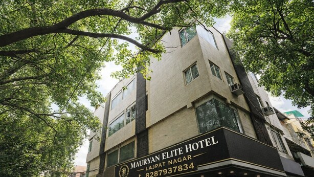 Un edificio de varios pisos con un cartel que dice 'MAURYAN ELITE HOTEL' y un número de contacto.