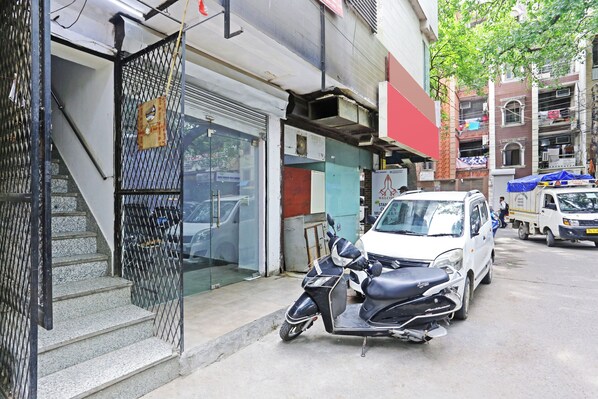 A scooter parked in front of a building with a metal gate and a staircase. - Mauryan Elite Hotel Lajpat Nager (New Delhi)