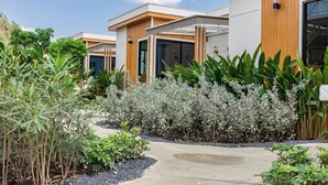 Een modern gebouw met een houten gevel, grote ramen en een tuin met diverse planten.