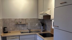 A compact kitchen with white cabinets, a dishwasher, a sink, and a stove. - Cozy 2 room apartment with all amenities near krka park (Bilice)