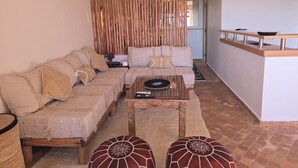 Una sala de estar con sofá, otomanas, una mesita de centro y un separador de madera.