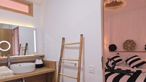 Un baño con tocador de madera, un lavabo blanco y un espejo con luz de aro.