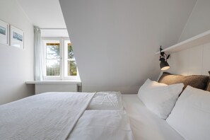 A bedroom with a bed, a desk, and a window. - Kleiner Dünenhof - Kampen (Sylt) (Kampen (Sylt))