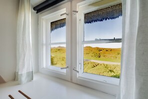 A room with two windows, white walls, and a view of a grassy landscape. - Kleiner Dünenhof - Kampen (Sylt) (Kampen (Sylt))