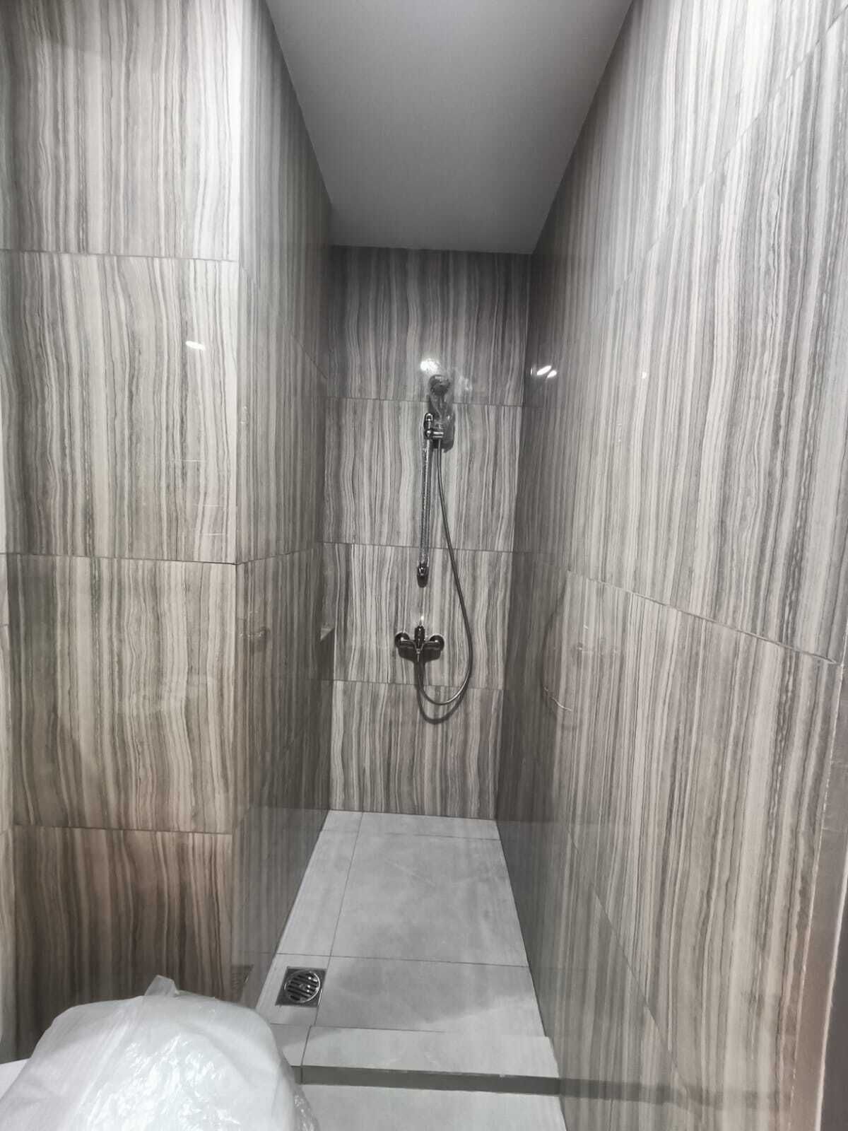 Una ducha moderna con cabezal de ducha manual y llave de pared fija.