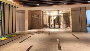 The entrance of a hotel with a modern design, featuring a prominent sign that reads "OMOR TOWER." - Apartmen Pakuwon Bekasi by Ruang Singgah (Bekasi)