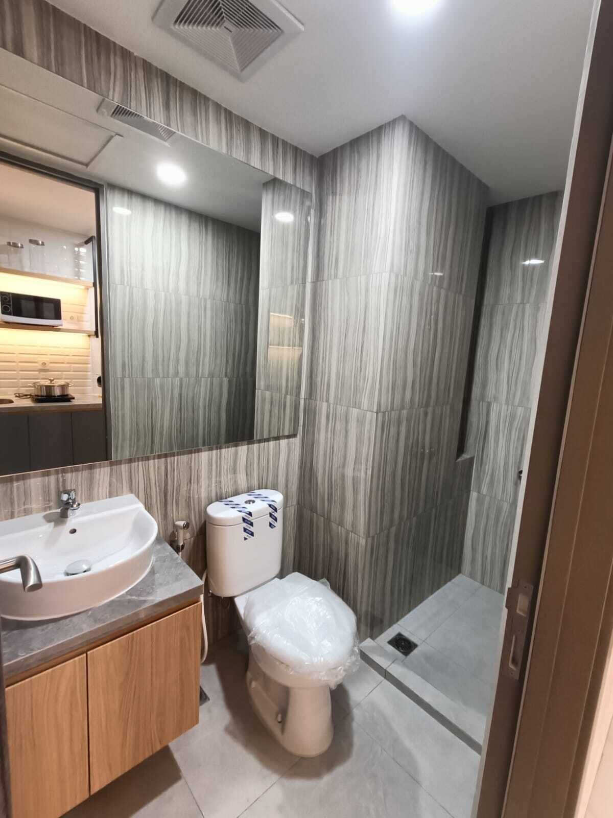 Une salle de bain moderne équipée d’un lavabo, de toilettes et d’une douche.