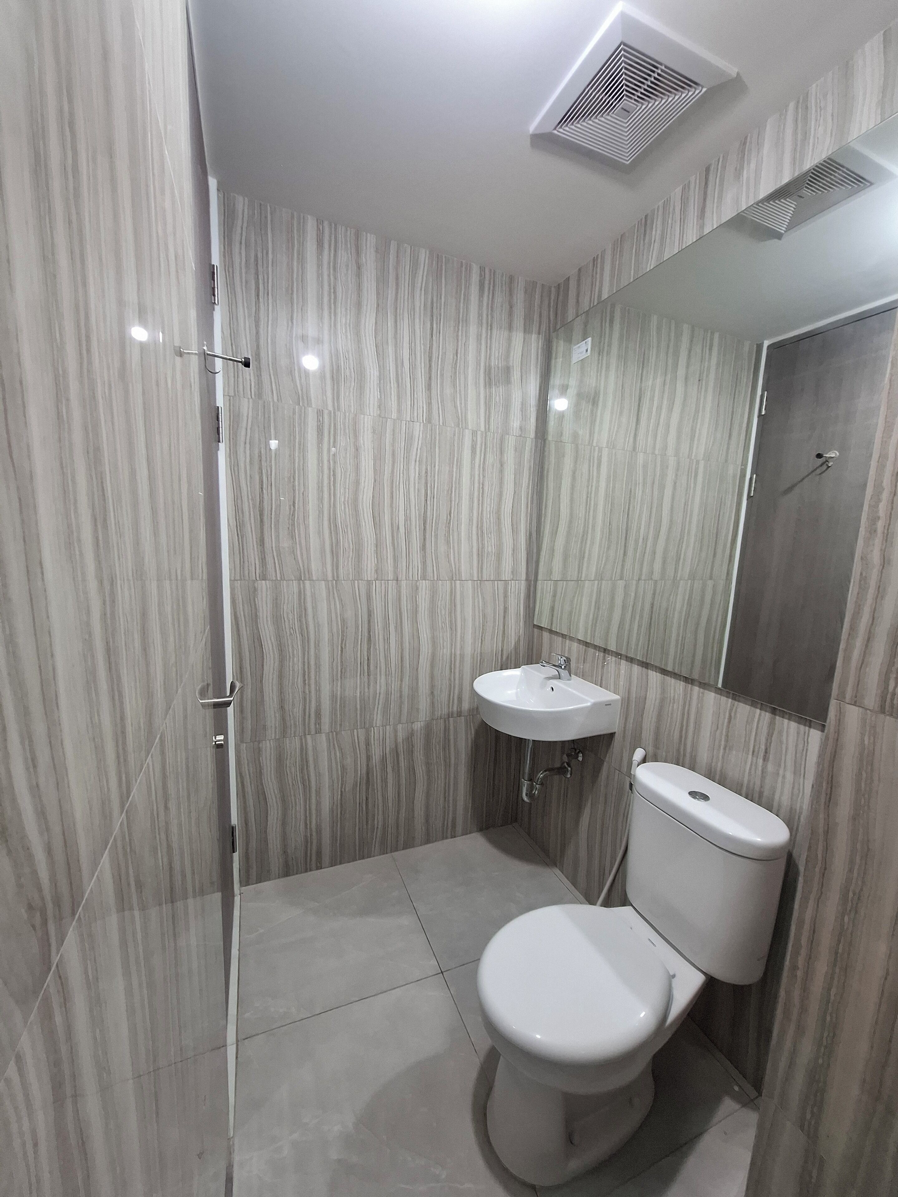 A bathroom with a toilet, sink, and mirror.