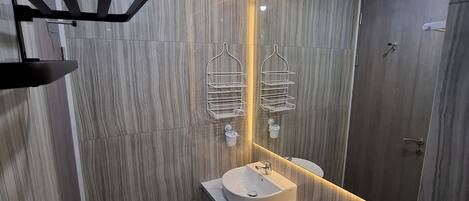 A modern bathroom with a vanity, sink, and toilet. There are two towel racks above the mirror, and a shower area is visible in the background.