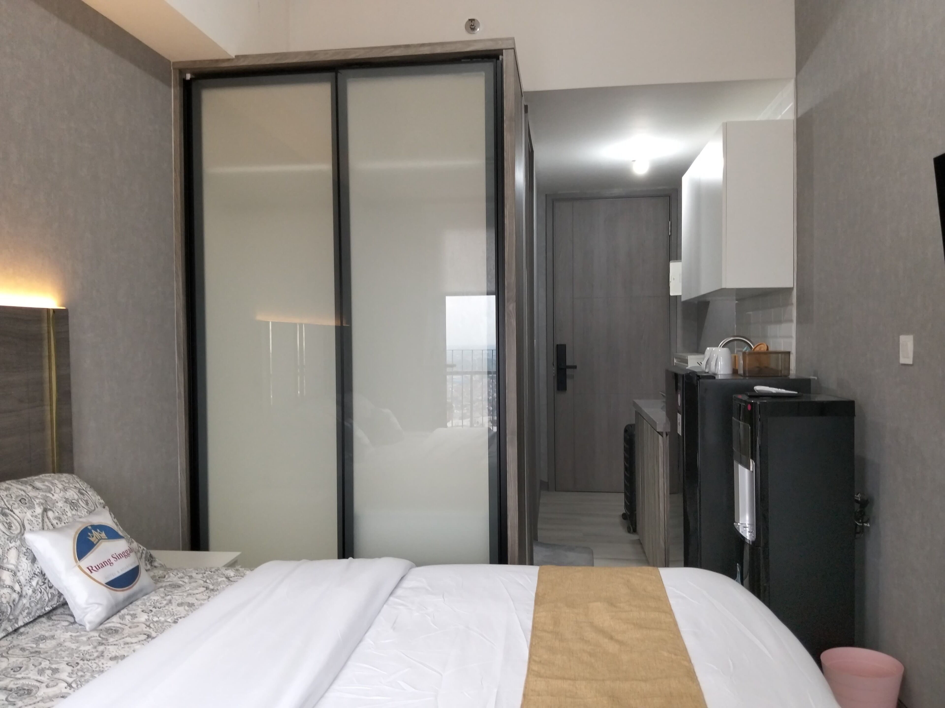 A hotel room with a bed, a wardrobe, a desk, and a bathroom.