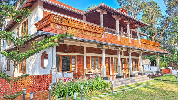 Un edificio a due piani con un balcone, un portico coperto e un giardino con piante e un tavolino.