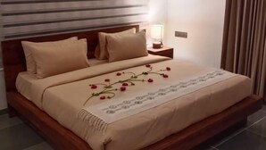 Un letto rifatto con cura, con copriletto floreale, una testata in legno e un comodino con una lampada.