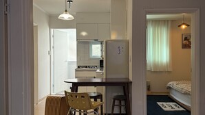 Une cuisine de taille réduite comprenant un réfrigérateur, une table à manger et une chaise.