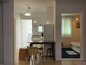 A compact kitchen with a refrigerator, a dining table, and a chair.