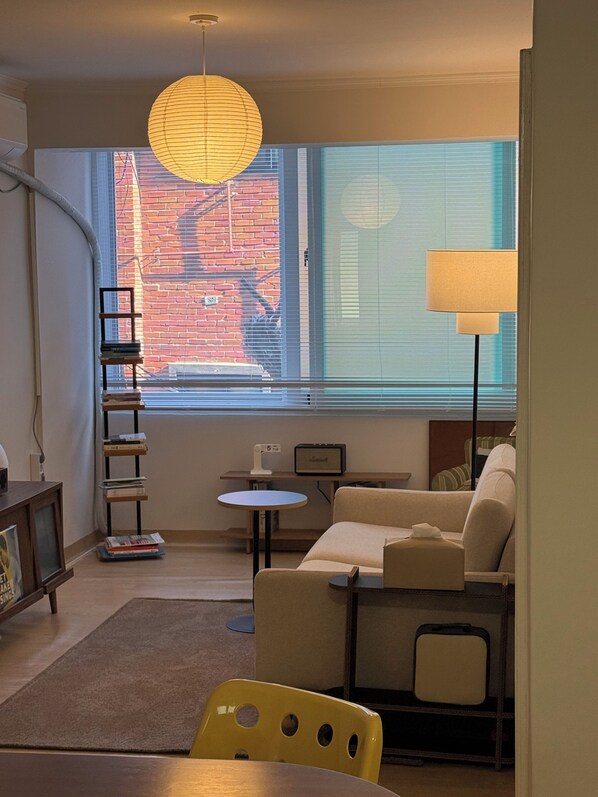 A compact living space with a sofa, a small table, a chair, a lamp, and a bookshelf.