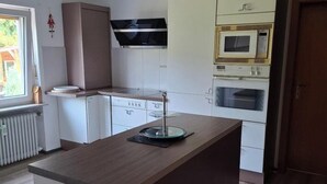Une cuisine moderne avec des meubles blancs, un îlot central, un four à micro-ondes et un four traditionnel.