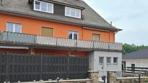 Une maison à deux étages avec un balcon, une cour clôturée et une antenne parabolique.