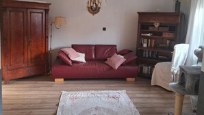 Un salon avec un canapé rouge, un meuble en bois, une bibliothèque et un arbre à chat.