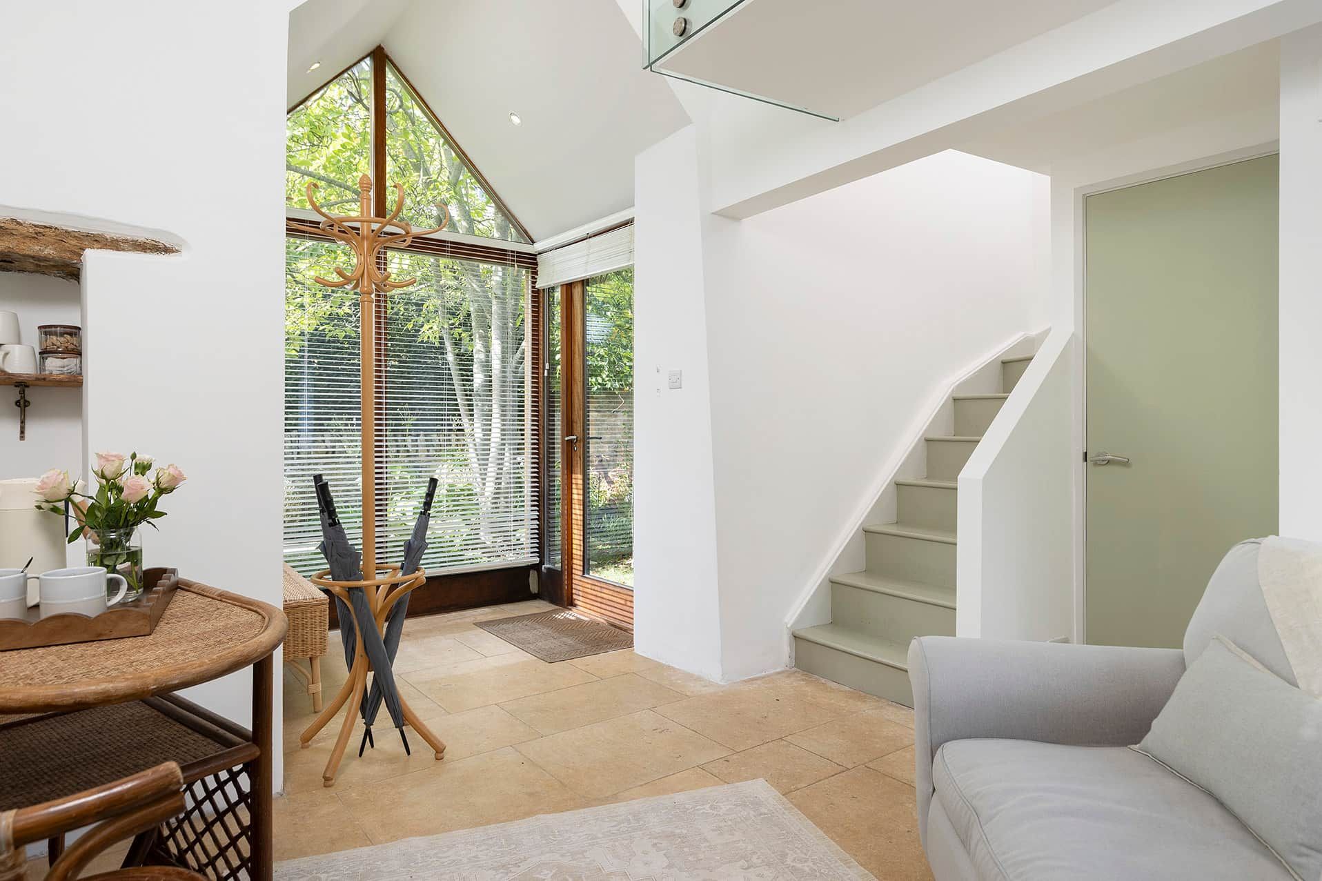 Ein modernes Interieur mit einer Treppe, einem Essbereich mit Tisch und Stühlen sowie einer Sitzecke mit einer Couch.
