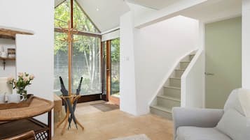 Ein modernes Interieur mit einer Treppe, einem Essbereich mit Tisch und Stühlen sowie einer Sitzecke mit einer Couch.