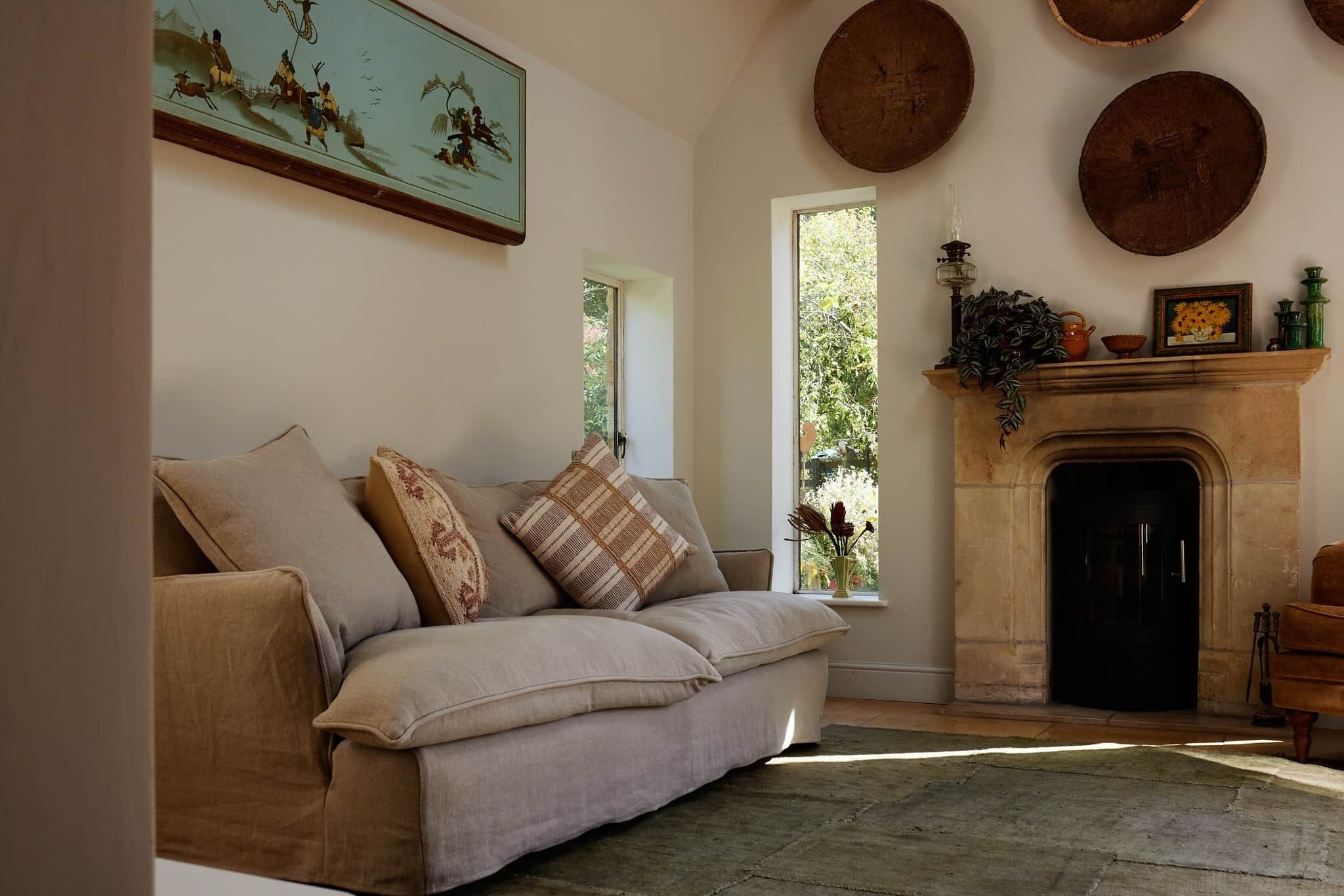 Ein Wohnzimmer mit einem beigefarbenen Sofa, einem Kamin und einem Gemälde an der Wand.