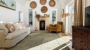 Una sala de estar acogedora con chimenea, un sofá, un sillón y un televisor.