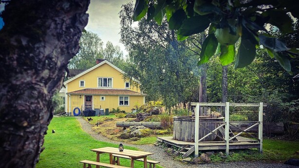 Una casa amarilla con un porche de madera y una mesa de picnic en el jardín.