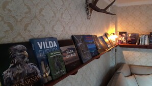 Una estantería con libros y un cráneo de animal colgado.
