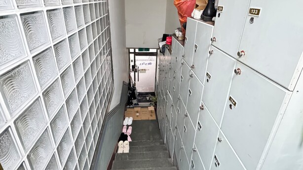 Un couloir étroit, avec des casiers d’un côté et un mur de verre de l’autre.