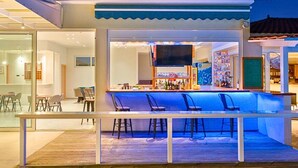 Eine Außenbar mit Theke, Barhocker und Blick auf das Nachbargebäude.