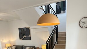 Una sala de estar moderna con una mesa de comedor redonda de madera, cuatro sillas de madera, una cafetera y un reloj en la pared.