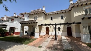 Un edificio de estilo español tradicional con un patio, mobiliario exterior y una pérgola.