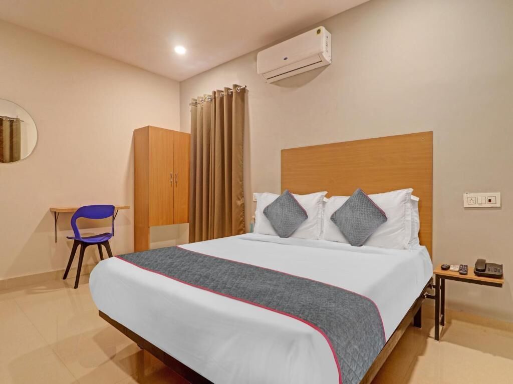 Habitación de hotel con cama, escritorio, silla, aire acondicionado y teléfono.