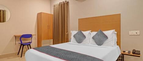 A hotel room with a bed, a desk, a chair, an air conditioning unit, and a telephone.