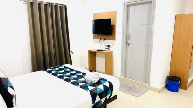 A hotel room with a bed, a TV mounted on the wall, a door, and a wardrobe. - White Ridge Hotel-Kphb (Hyderabad)