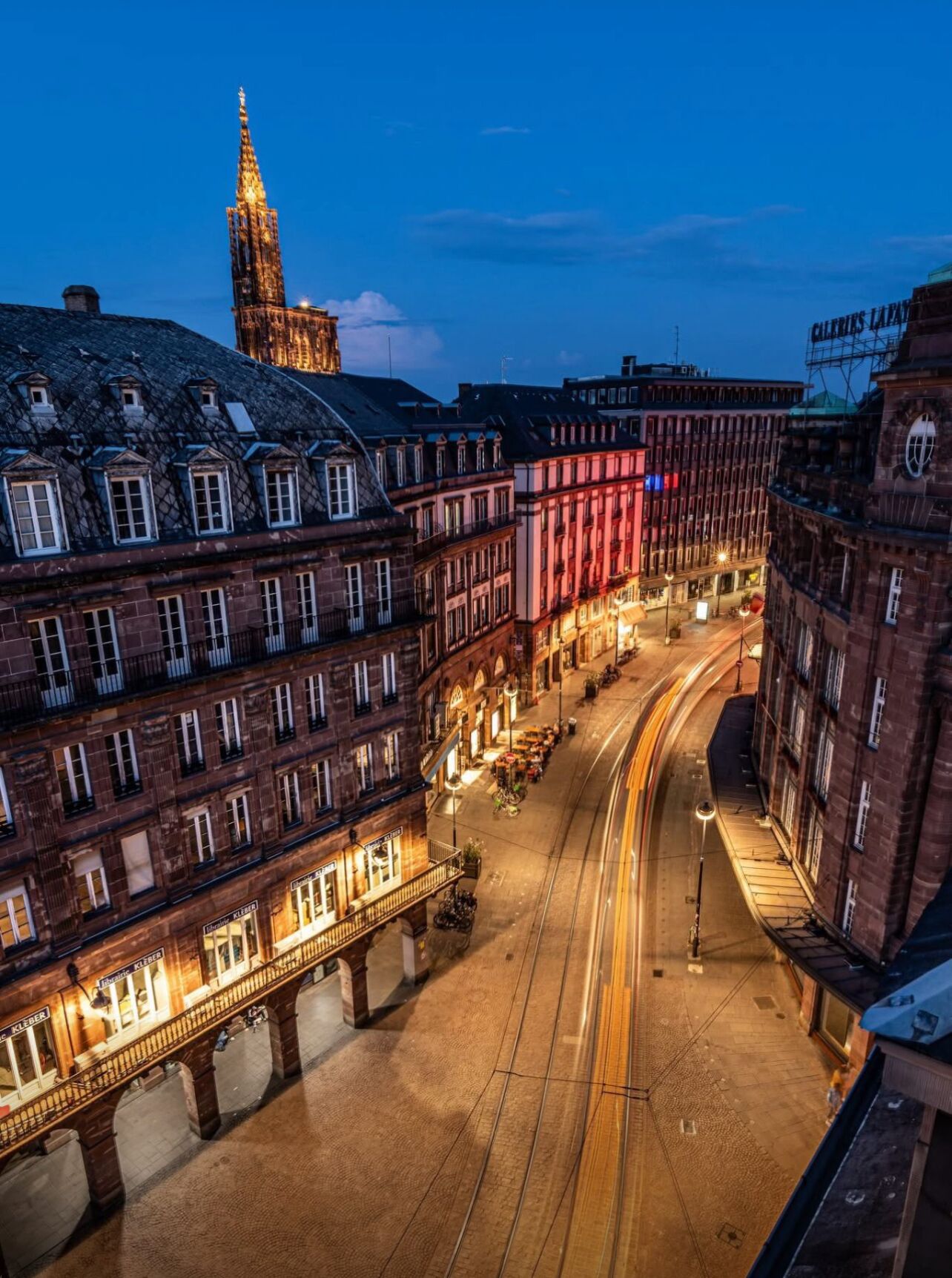 Een nachtzicht van een historisch Europees stadsplein met verlichte gebouwen en een opvallende toren.