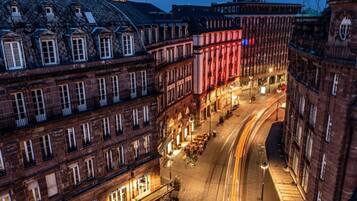 Een nachtzicht van een historisch Europees stadsplein met verlichte gebouwen en een opvallende toren.