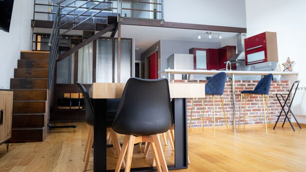 Een moderne keuken met een houten tafel, zwarte stoelen en een rode en witte koelkast.
