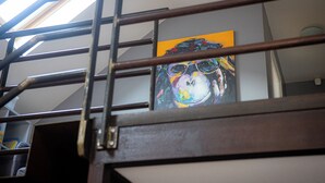 Een trap met een metalen leuning en een schilderij van een kleurrijk abstract gezicht op de muur.