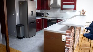 Een moderne keuken met rode kastjes, roestvrijstalen apparatuur en een wit aanrecht.