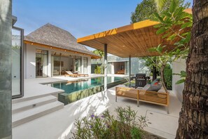 A modern house with a swimming pool, outdoor seating, and a covered patio area. - 3BR Pool Villa Mana at Anchan Tropicana (Thep Krasattri)